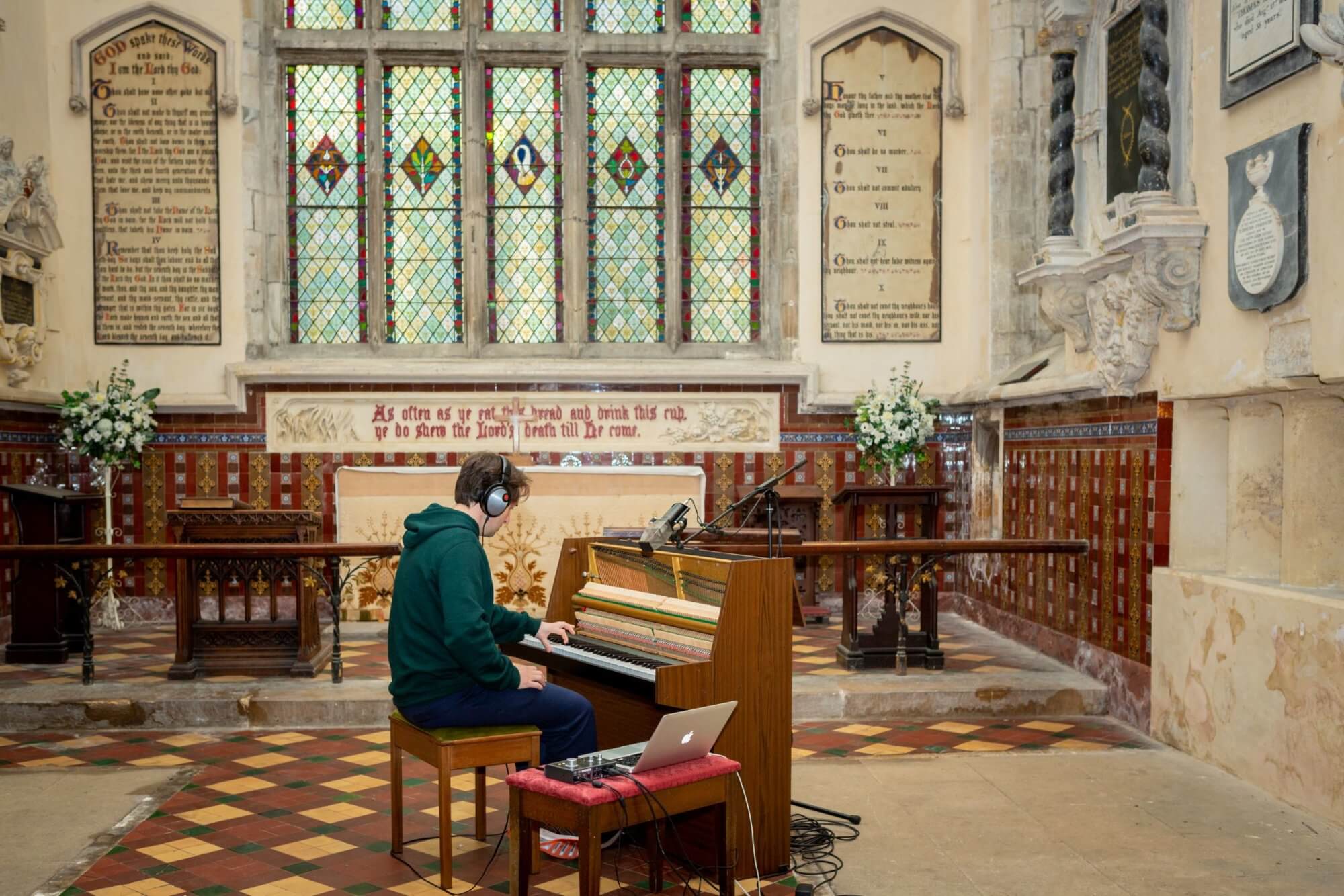 Man playing piano with mobile recording setup in a church