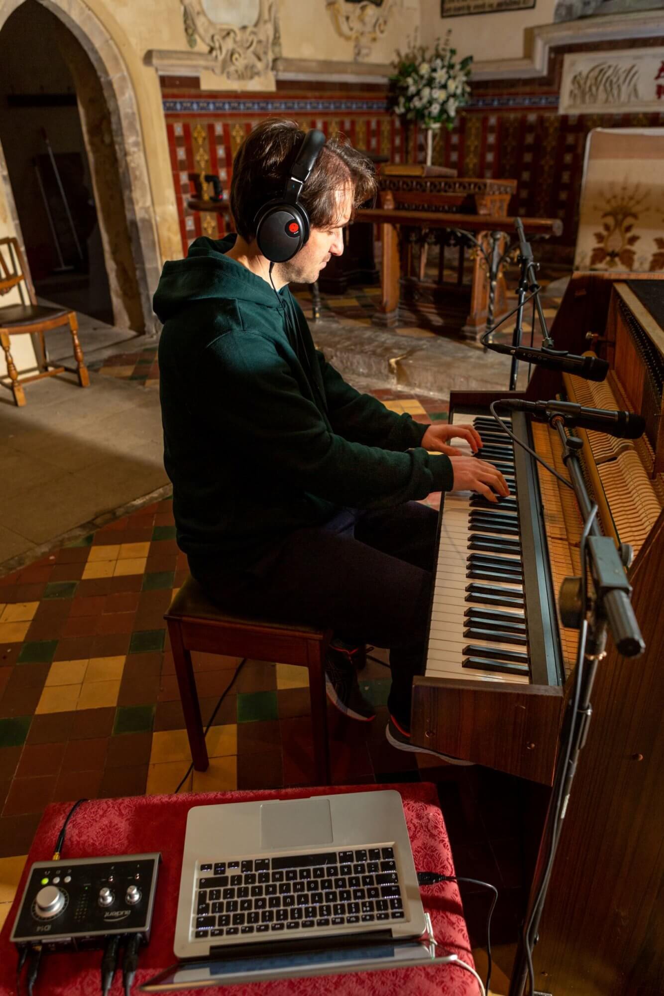 Man playing piano with mobile recording setup in a church
