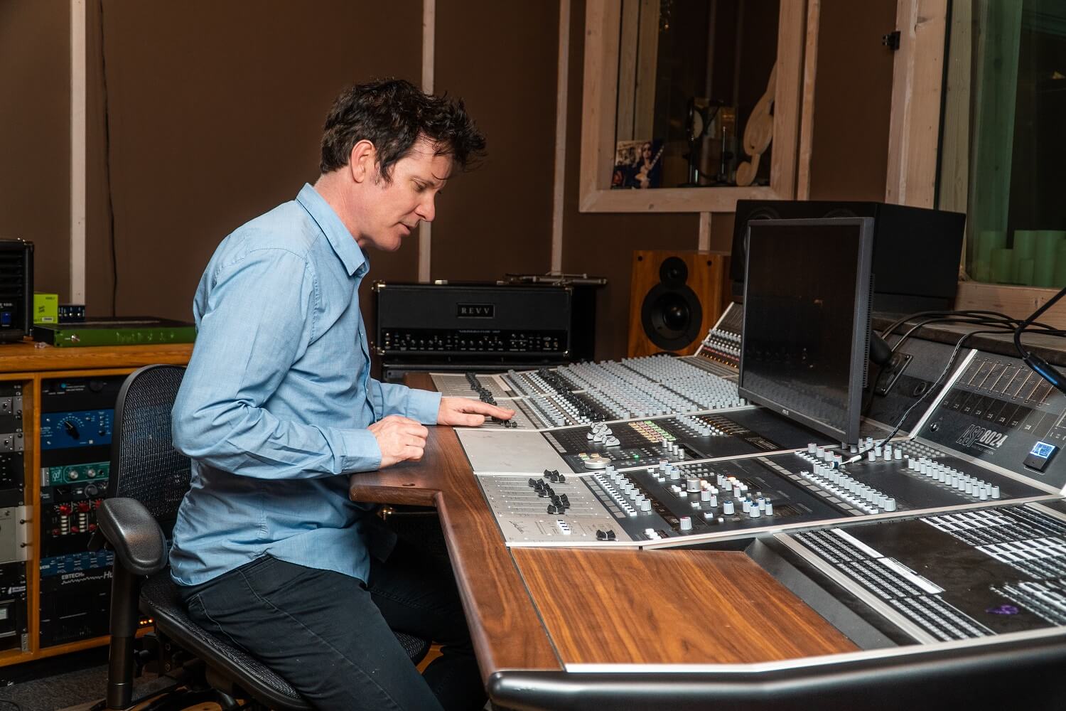 Man leans over mixing desk in recording studio