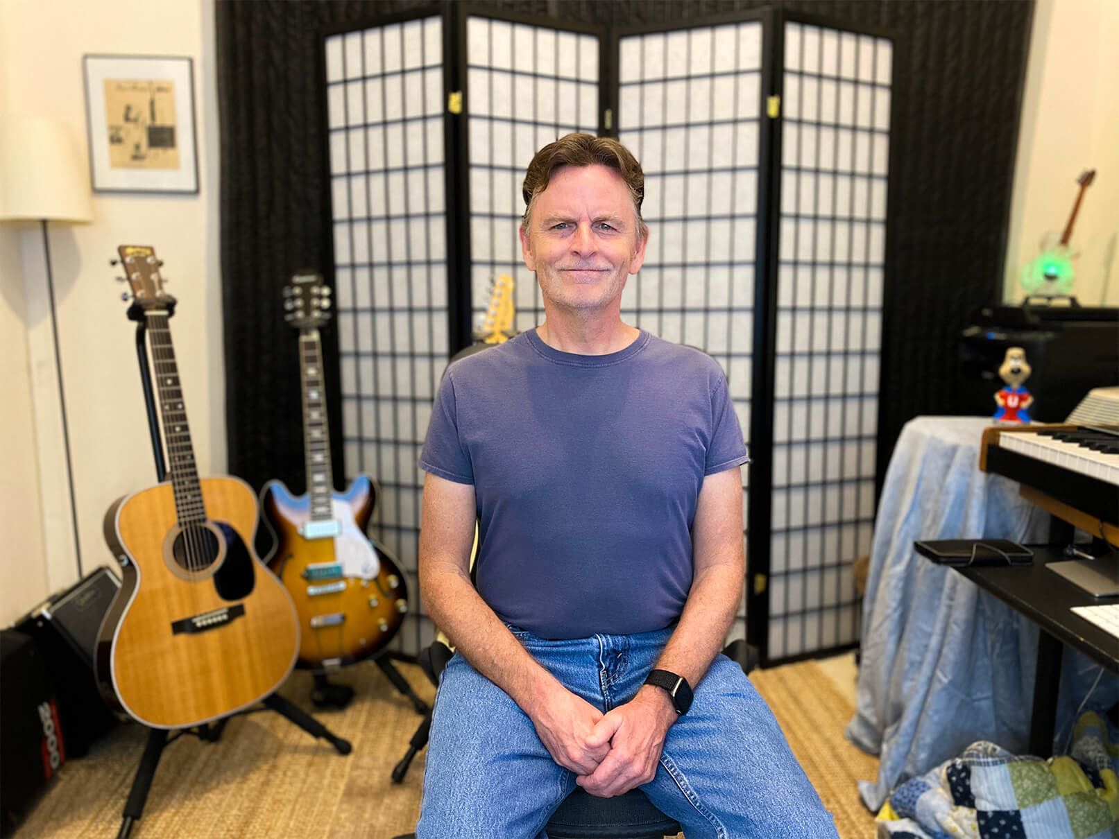 Man sits flanked by guitars in home studio