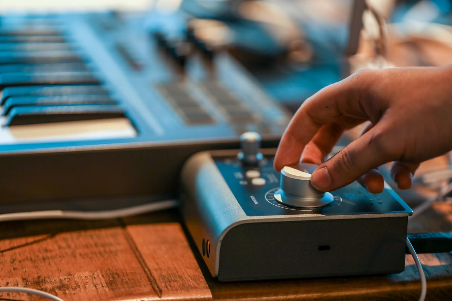 Audient iD4 audio interface with a hand on the iD knob and a keyboard blurred in the background