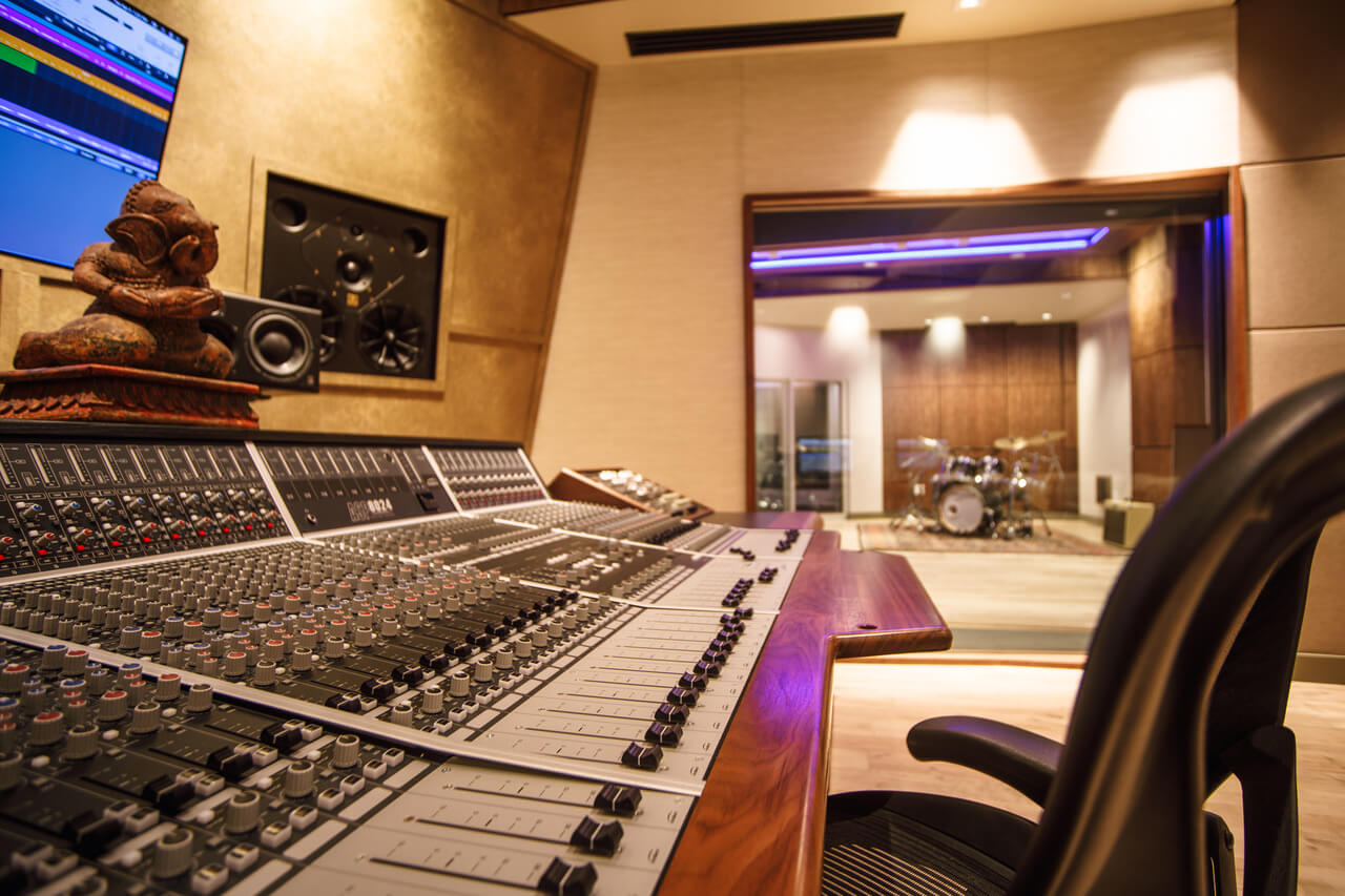 Large format mixing desk in foreground of large, open plan studio space