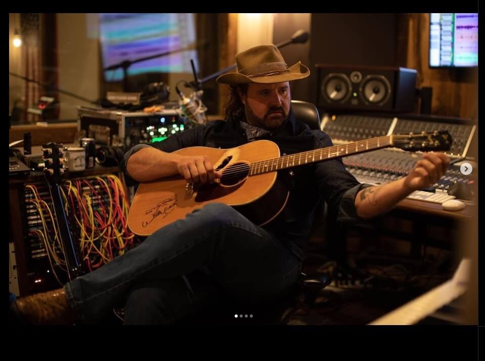 Randy Houser noodling on his guitar whilst sitting in his studio with the Audient ASP8024-HE mixing console. 