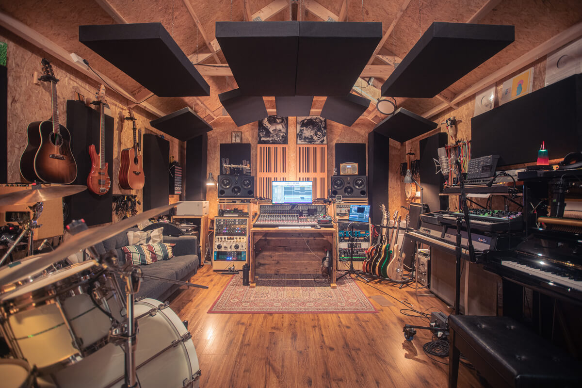 Music recording studio in a warehouse packed with gear featuring compact recording console at the far end
