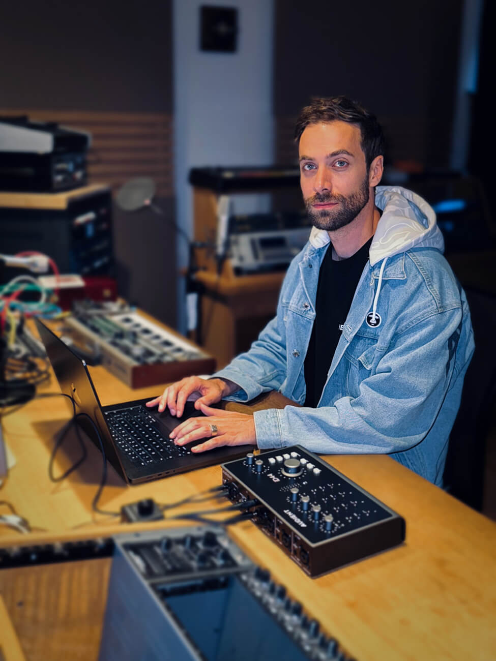 Morgan Avenue looks to camera whilst sitting at his laptop, with iD44 audio interface from Audient in foreground