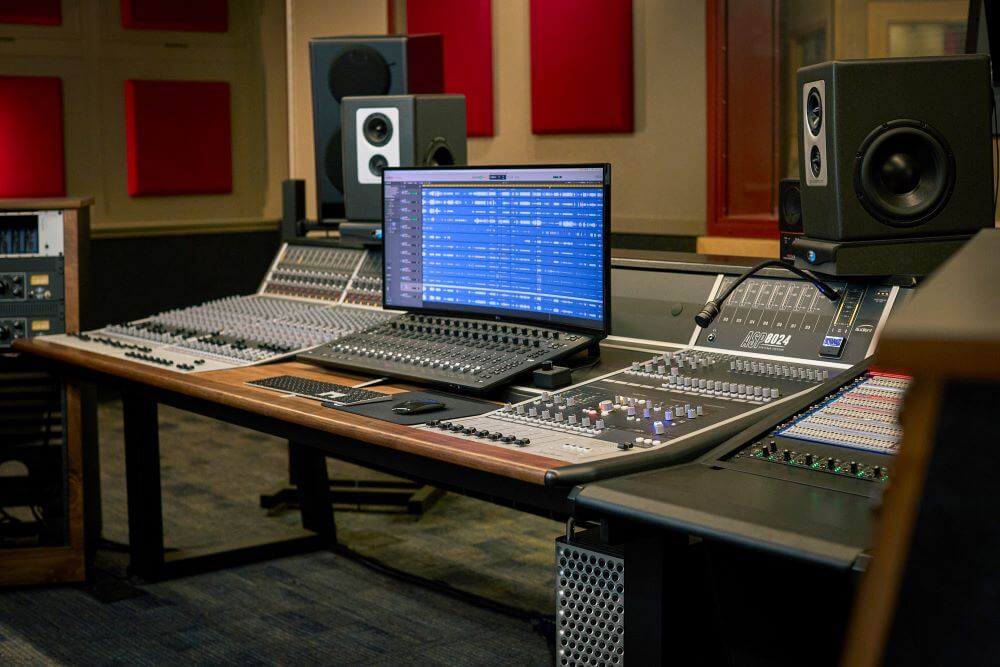 An Audient recording console in a well-stocked studio